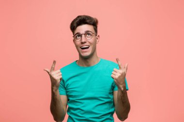 Genç, havalı, beyaz bir adam iki elini de havaya kaldırarak boş bir alan gösterdiğini gösteriyor..