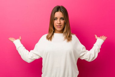 Bir duvara karşı Genç otantik karizmatik gerçek insanlar kadın kolları ile ölçek yapar, mutlu ve kendinden emin hissediyor.