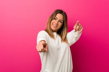 Bir duvara karşı genç otantik karizmatik gerçek insanlar kadın ön işaret neşeli gülümsüyor.