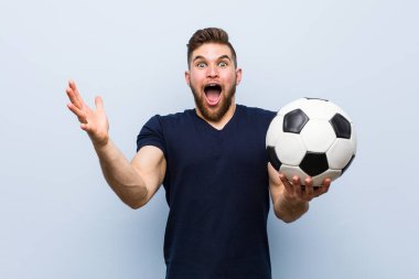 Genç beyaz adam bir zafer ya da başarı kutluyor bir futbol topu tutan