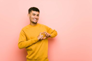 Genç İspanyol adam gülümseyen ve elleriyle bir kalp şekli gösteren.