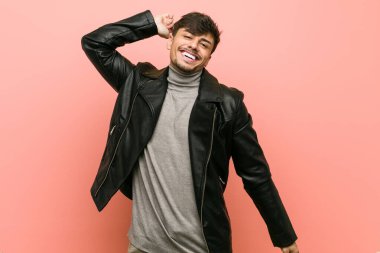 Deri ceket giyen, kollarını açarak rahatlayan genç İspanyol bir adam..