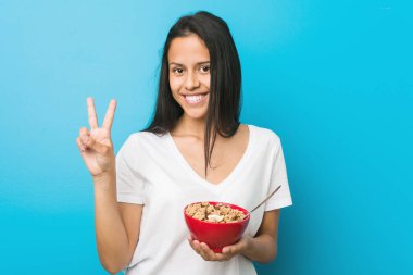 Genç İspanyol kadın elinde mısır gevreği kasesiyle iki numarayı parmaklarıyla gösteriyor..