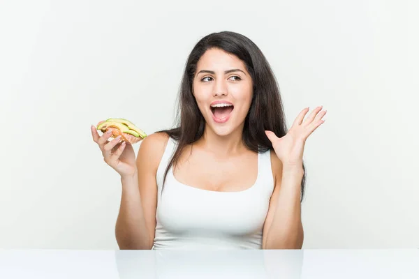 Young Hispanic Woman Holding Avocado Toast Celebrating Victory Success — Stockfoto