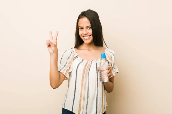 年轻的惊慌失措的女人拿着一瓶水 用手指显示二号 — 图库照片
