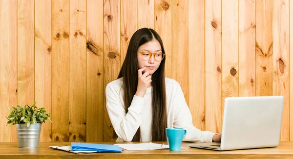 Joven Mujer China Estudiando Escritorio Mirando Lado Con Expresión Dudosa — Foto de Stock