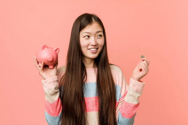 年轻的亚洲妇女拿着一个小猪银行 — 图库照片