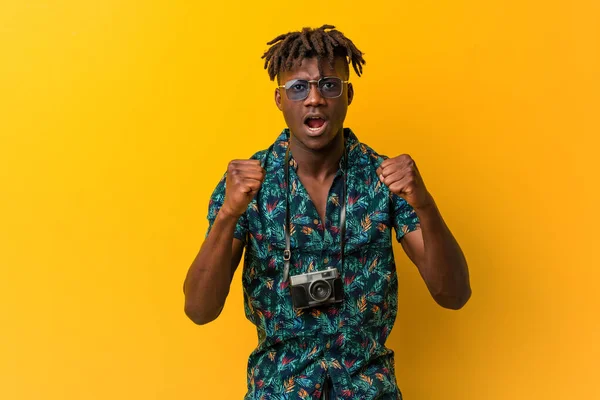 Young black rasta man wearing a vacation look cheering carefree and excited. Victory concept.