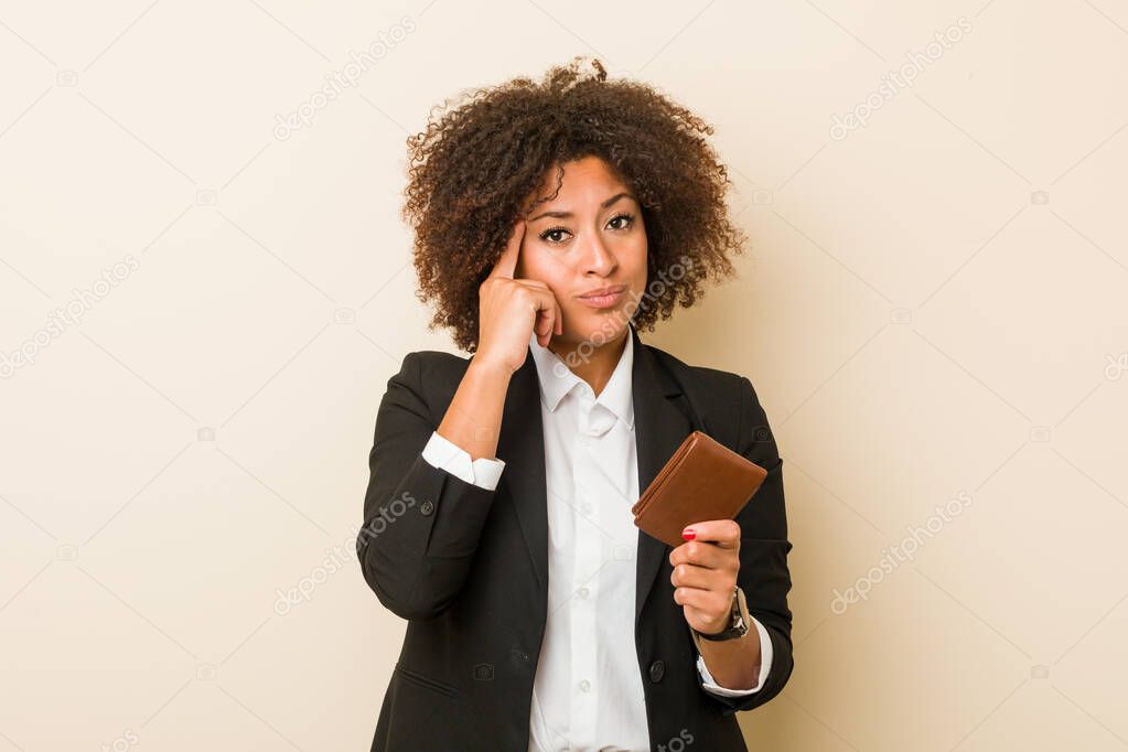 Young african american woman holding a wallet pointing his temple with finger, thinking, focused on a task.
