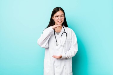 Genç Çinli doktor iki eliyle bir şey tutuyor, ürün sunumu..