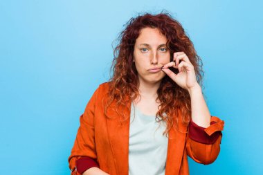 Genç kızıl saçlı, zarif bir kadın. Parmakları dudaklarında, sır saklıyor..