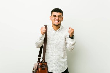 Genç İspanyol sıradan iş adamı yumruğunu kaldırıyor, mutlu ve başarılı hissediyor. Zafer konsepti.