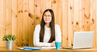 Masasında çalışan Çinli genç bir kadın amaçlarına ve amaçlarına ulaşmanın hayalini kuruyor.