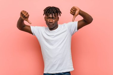 Genç Afrikalı siyahi adam baş parmağını aşağı gösteriyor ve hoşlanmadığını ifade ediyor..