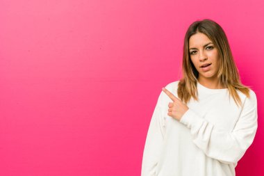 Genç otantik karizmatik gerçek insanlar kadın bir duvara karşı gülümseyen ve bir kenara işaret, boş alanda bir şey gösteren.