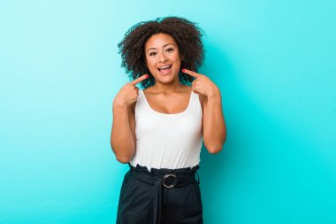 Genç Afrikalı Amerikalı kadın gülümsüyor, parmaklarını ağıza doğrultuyor..