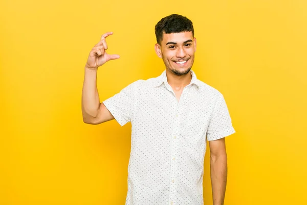 Mladý Hispáný Muž Držící Prstech Cosi Malého Usmívajícího Sebevědomého — Stock fotografie