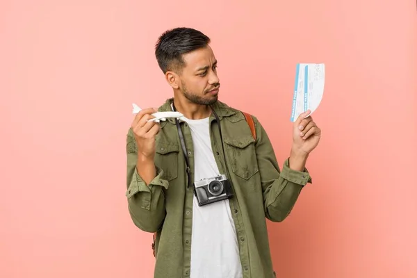 man with toy plane and tickets in hands on pink background