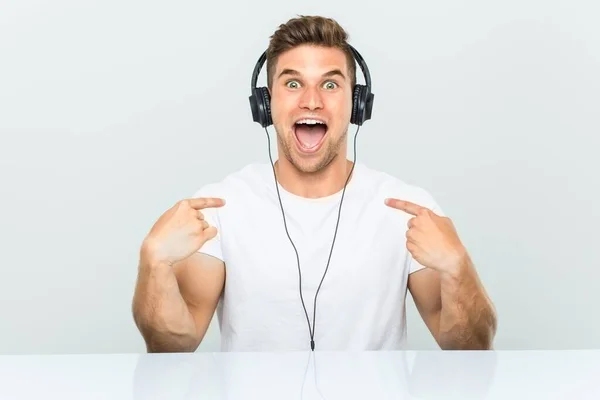 Joven Escuchando Música Con Auriculares Sorprendido Apuntándose Mismo Sonriendo Ampliamente — Foto de Stock