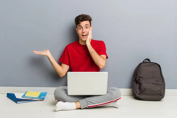 Jonge student man zittend op zijn huis vloer met een laptop — Stockfoto