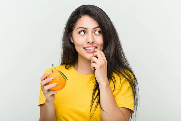 Young Hispanic Woman Holding Orange Relaxed Thinking Something Looking Copy Stock Image