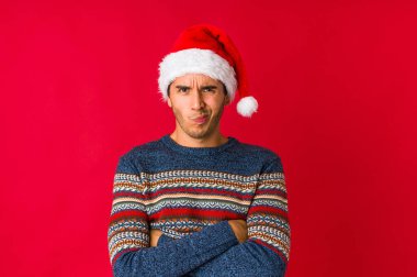 Genç adam noel gününde düşünceli bir şekilde ağzını kapayan bir fotokopi odasına bakıyor..