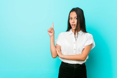 Mavi bir duvara yaslanmış genç Latin asıllı havalı bir kadın. Harika bir fikri var. Yaratıcılık kavramı..