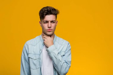 Kot gömlek giyen genç yakışıklı öğrenci virüs ya da enfeksiyon yüzünden boğaz ağrısı çekiyor..