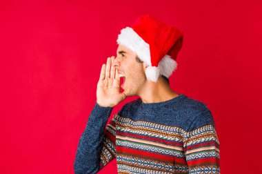 Noel gününde genç bir adam kameraya parmaklarıyla göz kırpıyor, yüzünü kapatmaktan utanıyor..