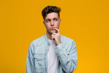 Kot gömlek giyen genç yakışıklı bir öğrenci şüpheli ve şüpheci bir ifadeyle yana bakıyor..