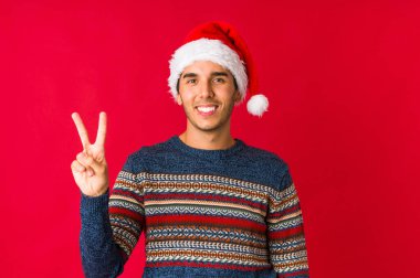 Genç adam Noel gününde kendine güveniyor, ellerini kalçasında tutuyor..