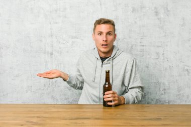 Masada bira içen genç adam, avuç içinde fotokopi yeri tutmaktan etkilendi..