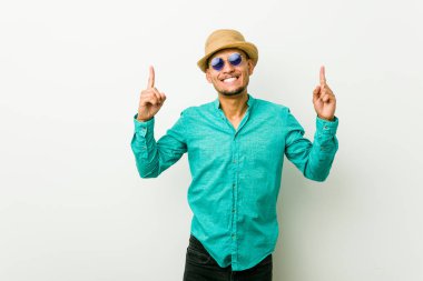 Yaz kıyafetleri giyen genç İspanyol adam iki parmağını da havaya kaldırarak boş bir alan gösterdiğini gösteriyor..