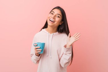 Zaferi ya da başarıyı kutlayan bir kupa tutan genç Arap kadın.