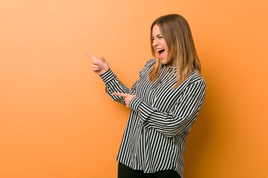 Genç otantik karizmatik gerçek insanlar kadın bir duvara karşı heyecanlı forefingers uzakta işaret.