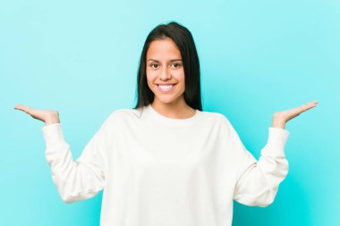 Genç ve güzel İspanyol kadın kollarıyla ölçek yapıyor, mutlu ve kendinden emin hissediyor..