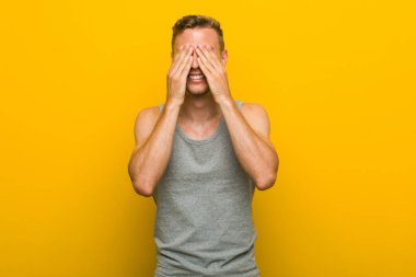 Genç kafkas spor adamı elleri ile gözleri kaplıyor, geniş bir sürpriz bekliyor gülümsüyor.