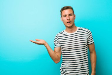 Mavi duvara yaslanmış beyaz bir genç, avuç içinin fotokopi alanını elinde tutmaktan etkilenmiş..