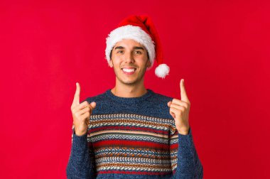 Genç adam Noel günü mutlu bir şekilde güler ve ellerini karnının üstünde tutarak eğlenir..