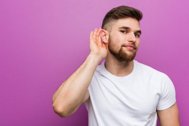 Young handsome caucasian man trying to listening a gossip.
