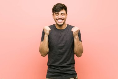 Genç İspanyol rahat adam yumruk yükselterek, mutlu ve başarılı hissediyorum. Zafer kavramı.