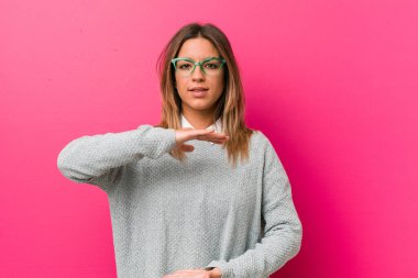 Genç otantik karizmatik gerçek insanlar kadın bir duvara karşı iki eliyle bir şey tutan, ürün sunumu.