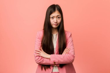 Pembe takım elbiseli genç Çinli kadın kameraya alaycı bir ifadeyle bakıyor..