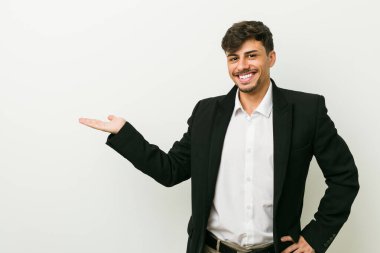 Genç bir İspanyol iş adamı avucunun içinde fotokopi odası gösteriyor ve elini belinde tutuyor..