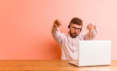 Çağrı merkezinde çalışan genç adam baş parmağını aşağı gösteriyor ve hoşlanmadığını ifade ediyor..