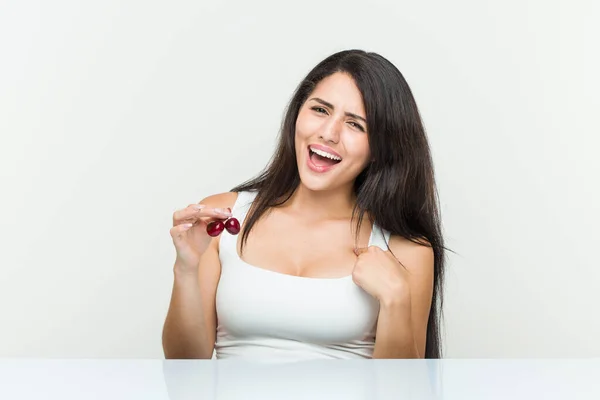 Joven Mujer Hispana Sosteniendo Cerezas Sorprendida Apuntándose Misma Sonriendo Ampliamente —  Fotos de Stock