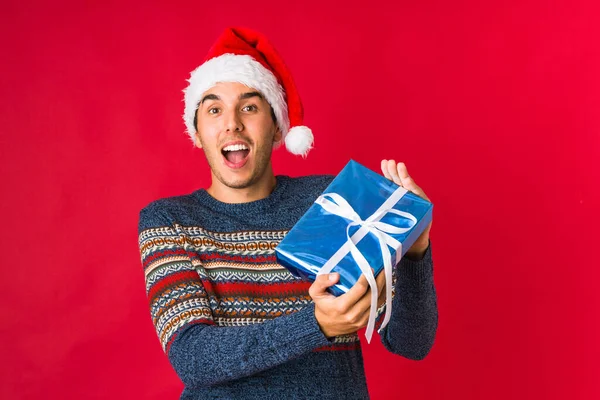 Junger Mann hält ein Geschenk an Weihnachten in der Hand — Stockfoto