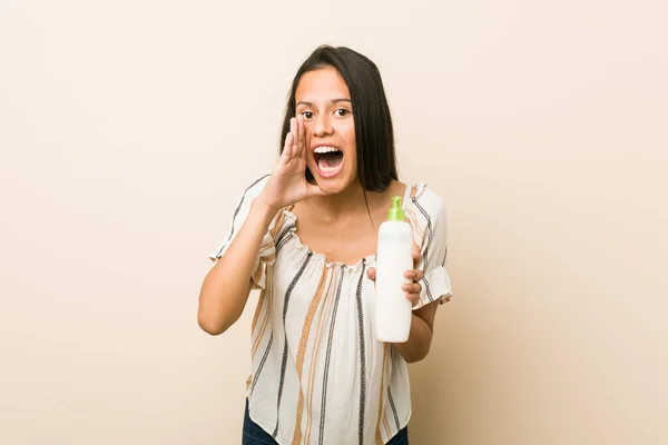 Junge Hispanische Frau Hält Eine Cremeflasche Und Schreit Aufgeregt Nach — Stockfoto