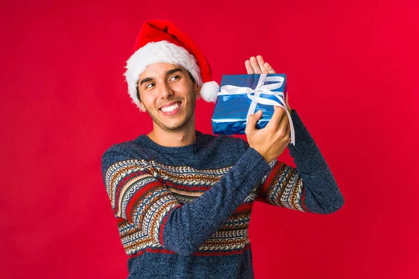 Junger Mann hält ein Geschenk an Weihnachten in der Hand — Stockfoto