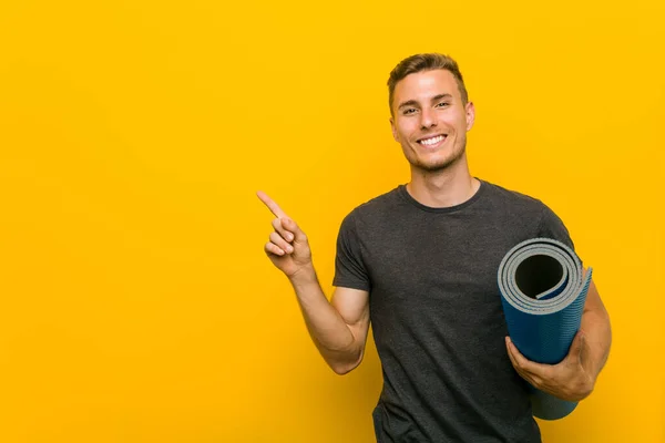 Joven Hombre Caucásico Sosteniendo Una Alfombra Sonriendo Alegremente Señalando Con — Foto de Stock